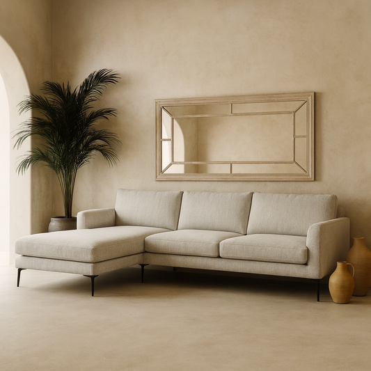 Beige sectional sofa in a room with a mirror, plant, and vases.