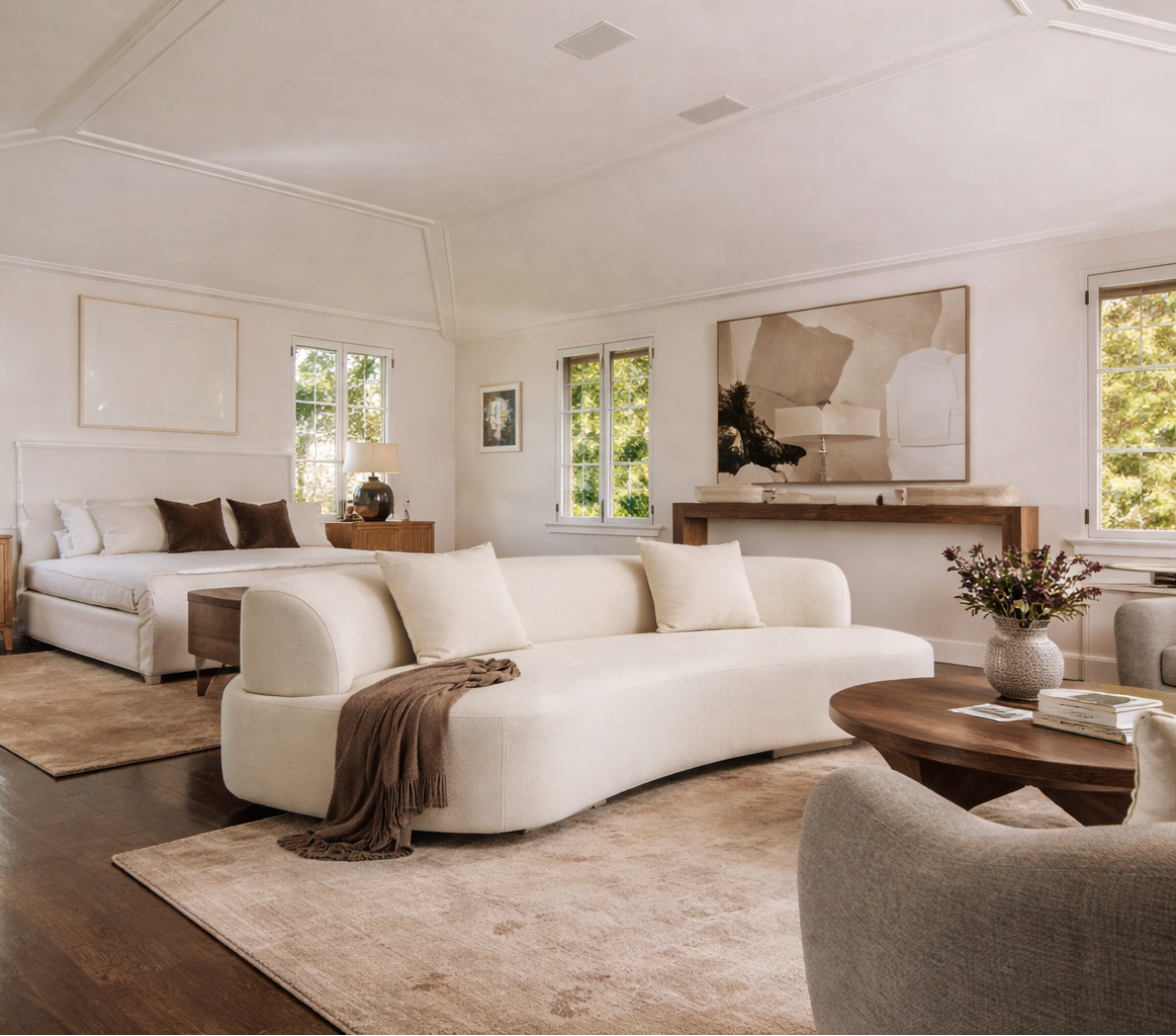 Modern bedroom with white sofa, wooden coffee table, and large windows.