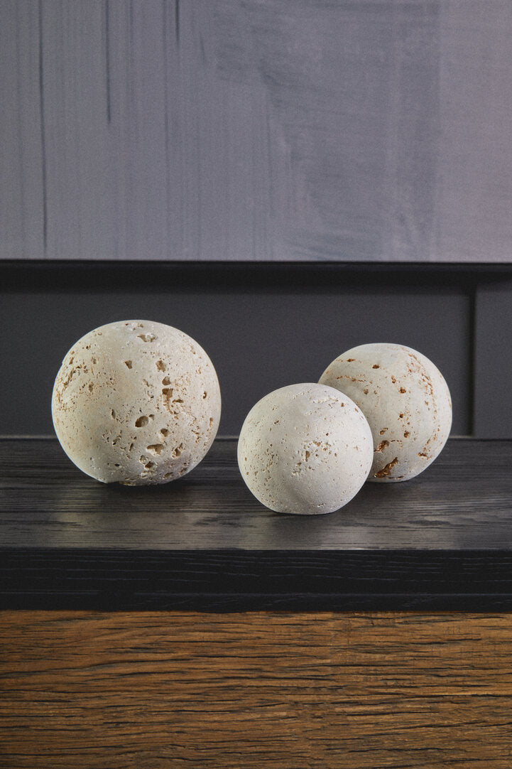 Three textured stone balls on a wooden surface with a dark background