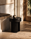 Dark wooden side table with a small decorative object in a softly lit room.