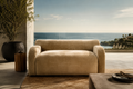 Beige sofa in a room with a large window view of the ocean.