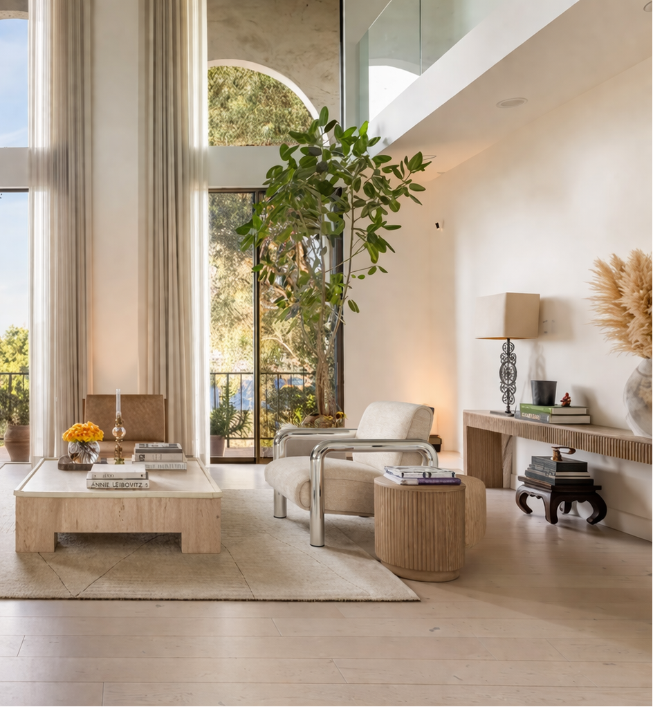 Chrome & Cream accent chair in a Modern living room with large windows, neutral decor, and a view of greenery outside.
