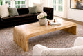 Living room with a wooden coffee table, dark sofa, and white rug.