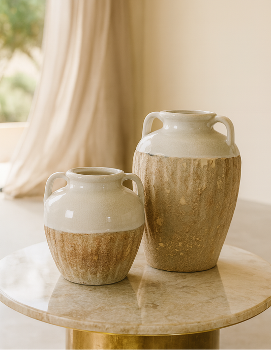 Two ceramic vases on a marble table with a blurred curtain background