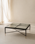 Modern coffee table with glass top and metal frame in a minimalistic room.